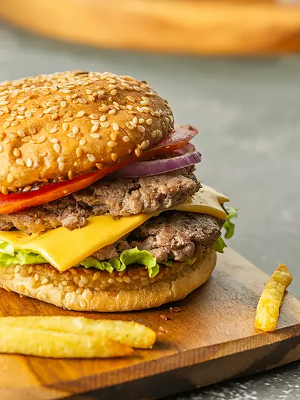 Burger généreux et frites posés sur une planche en bois